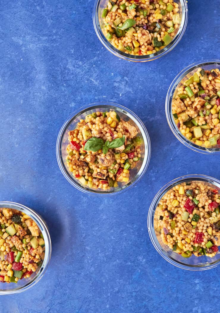 Nandos inspired giant couscous salad divided into meal prep containers with peri peri chicken
