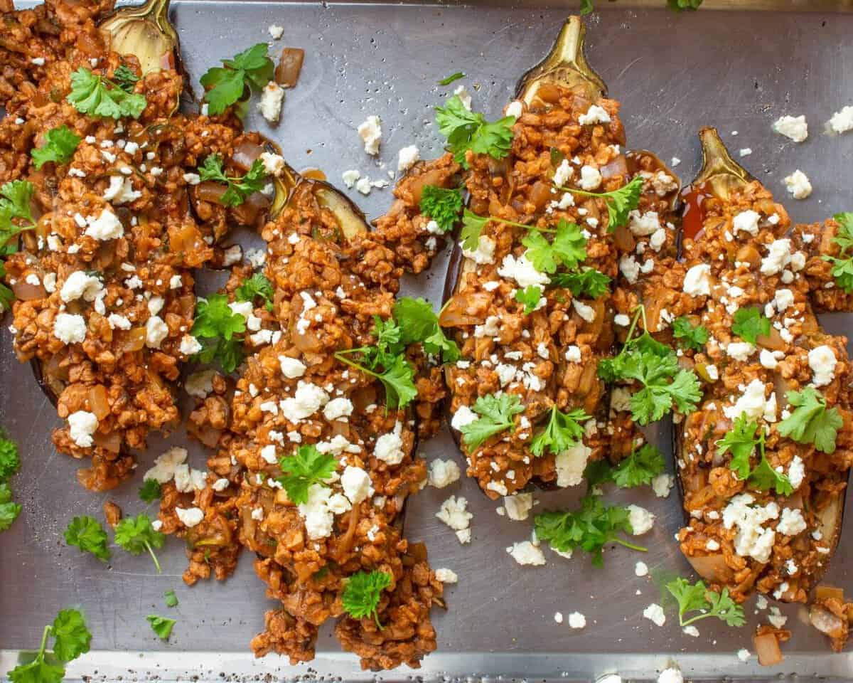 Moroccan Inspired Veggie Aubergines (4 halves of aubergine with meat free filling) on stainless steel baking tray.