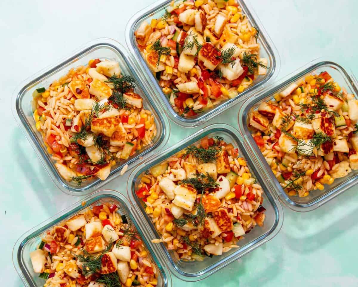 5 square glass meal pprep containers with orzo pasta salad with halloumi topped with some dill.