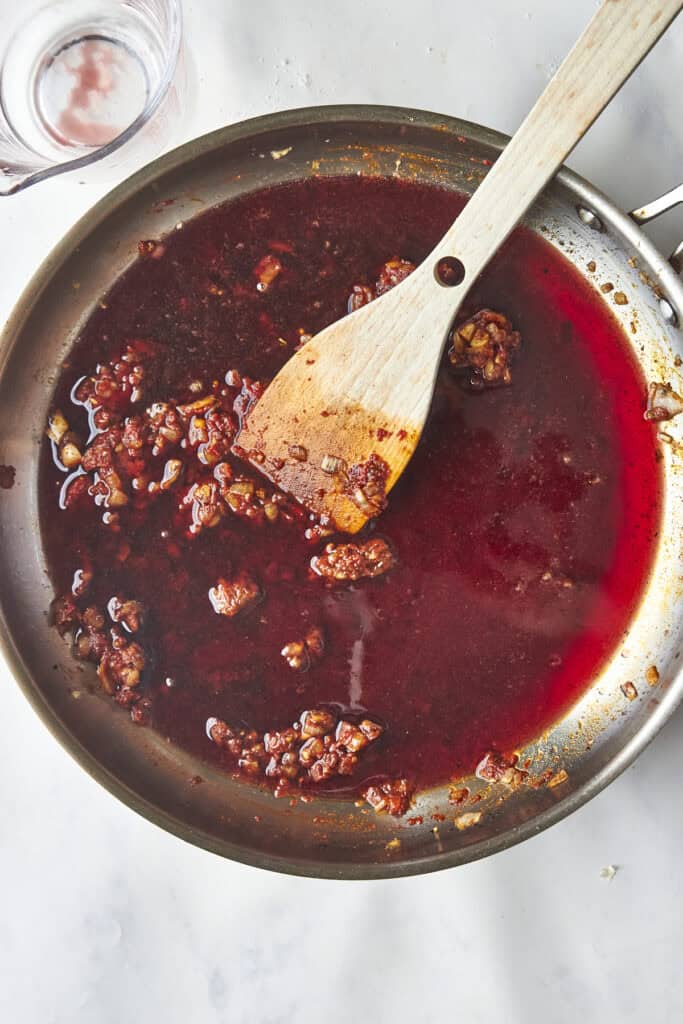 Seared oxtails being returned to the pot to simmer in the braising liquid.