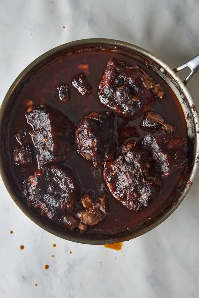 Fat being skimmed from the braised oxtail sauce before scattering with parsley.