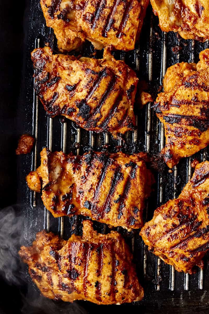 Close-up of charred copycat chipotle chicken thighs sliced on a board.