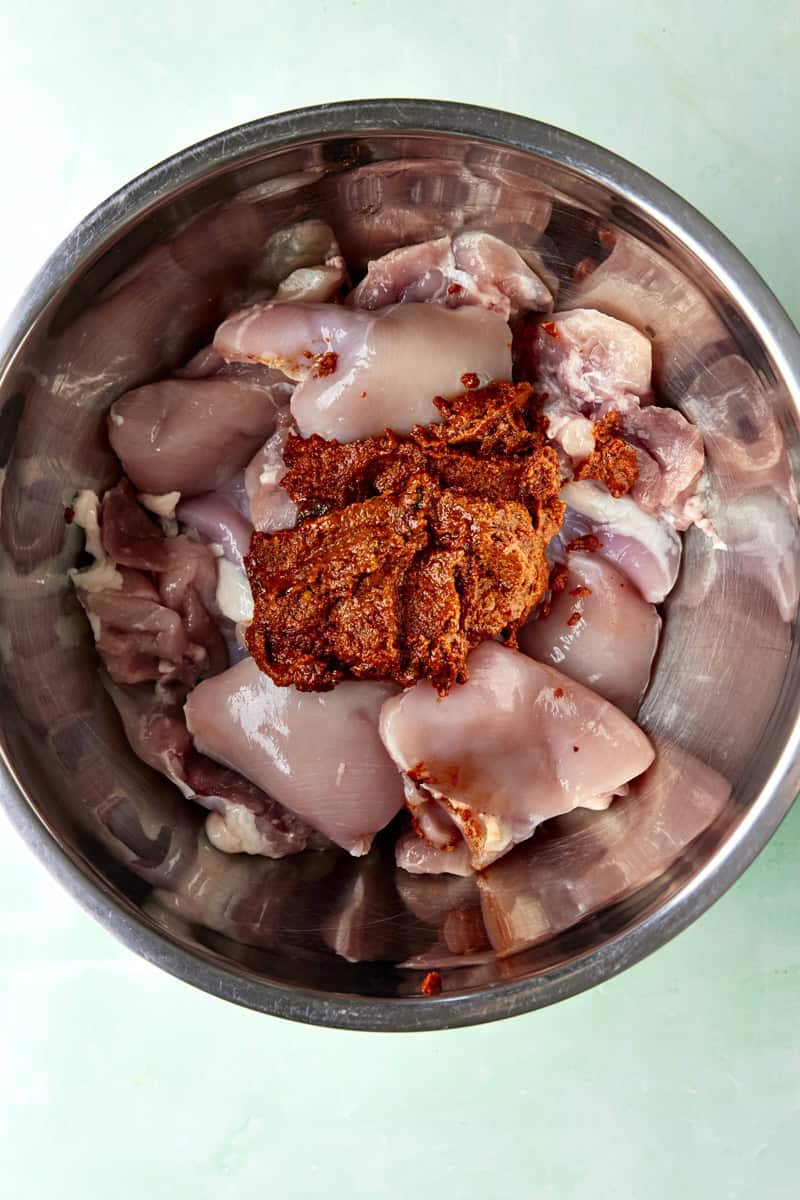 Marinade poured over chicken thighs, tossed to coat before marinating.