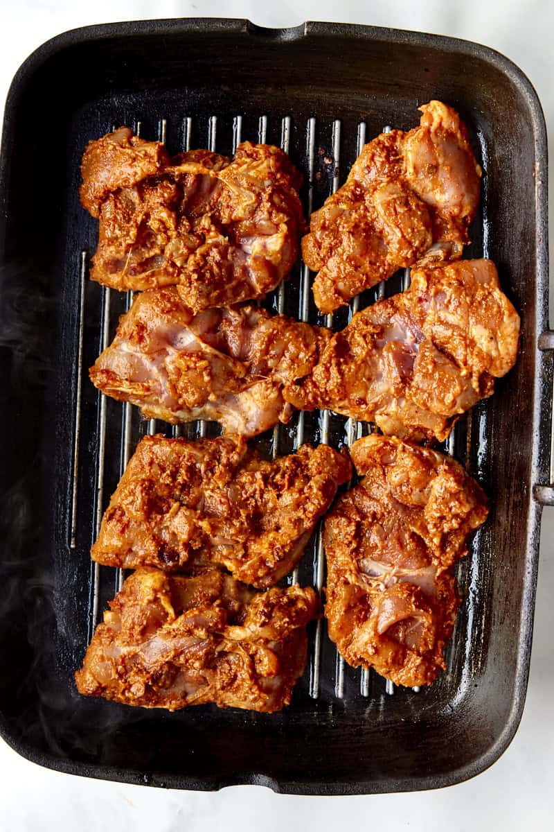 Chipotle chicken thighs charring on a hot griddle pan.