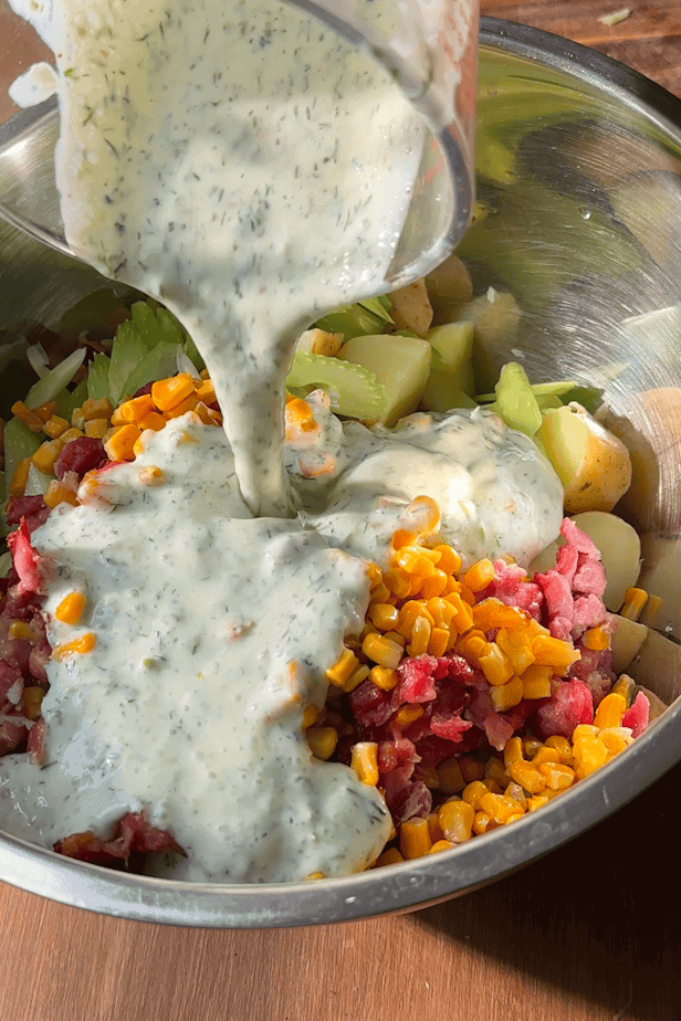 Creamy dill potato salad divided into five meal prep containers, topped with fresh dill.