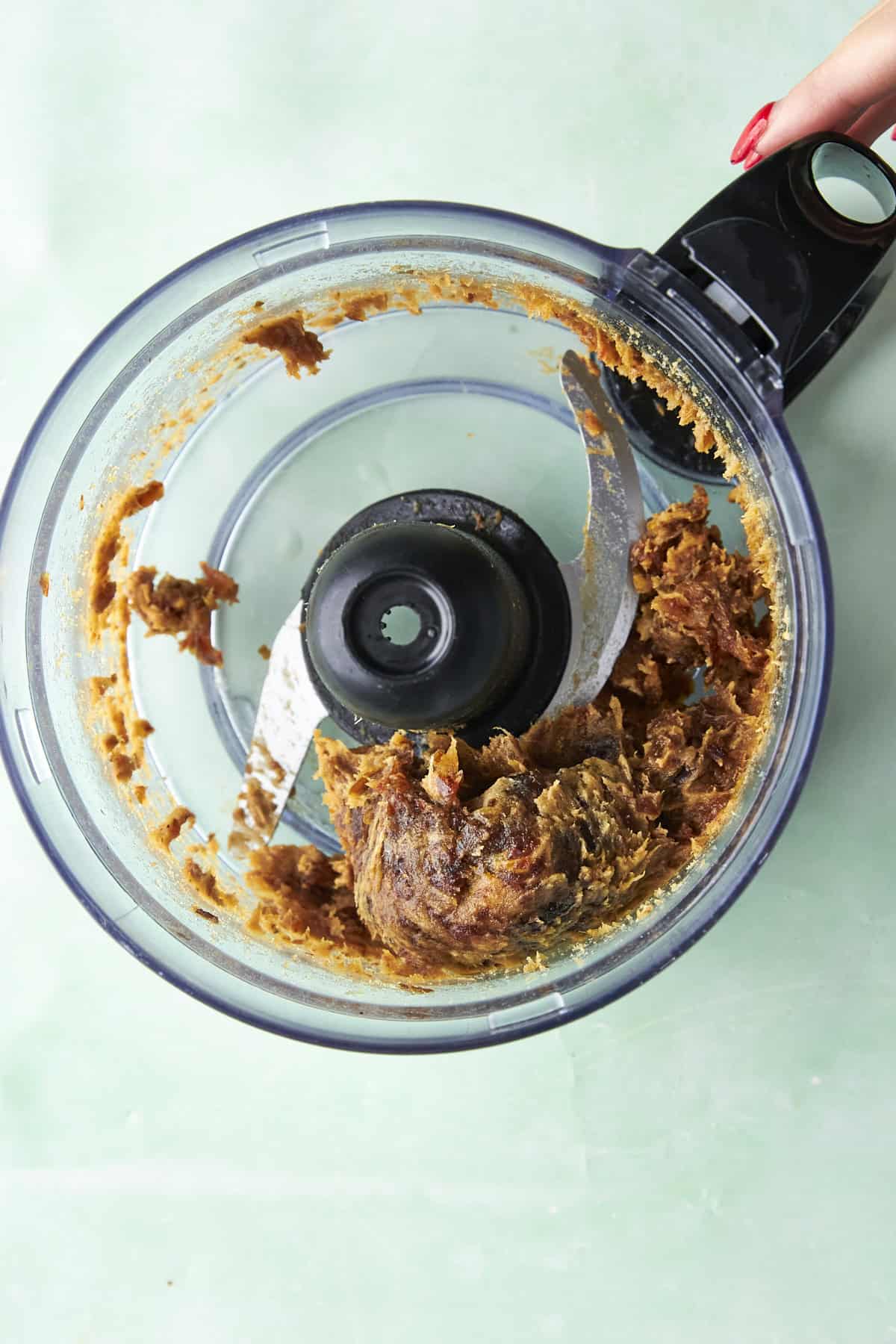 Blitzed date and almond butter mixture clumping together in the food processor.