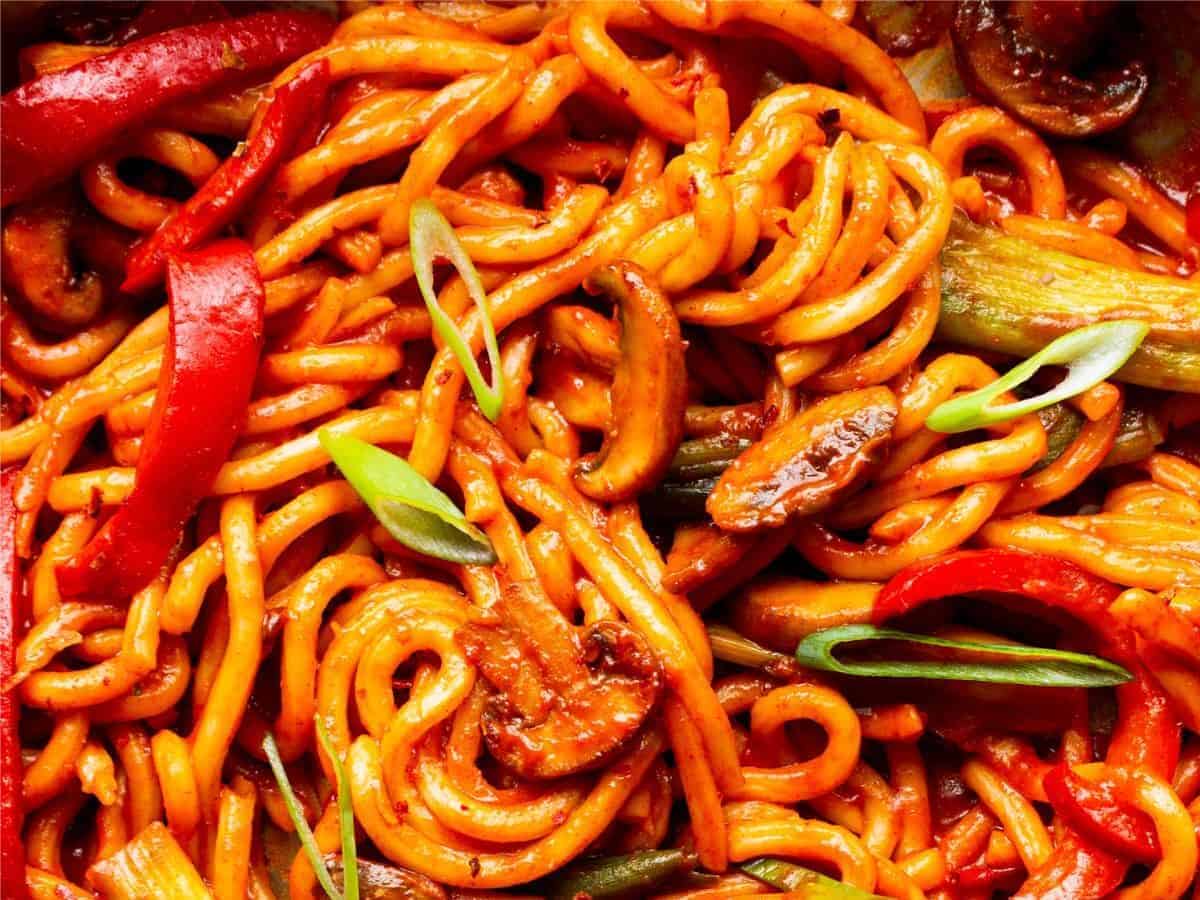Close up of noodles in tomatoey sauce with vegetables.