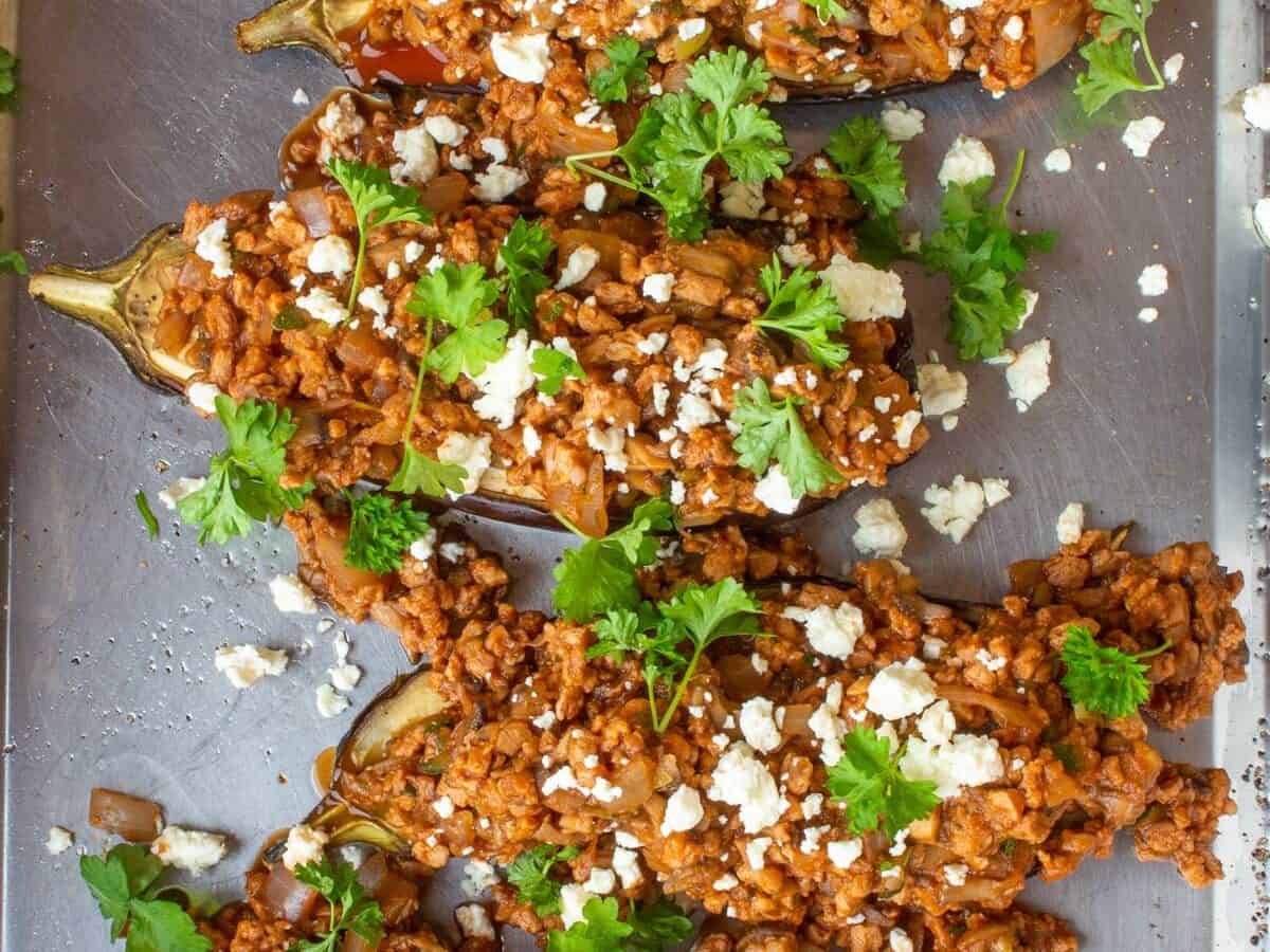 Moroccan Inspired Veggie Aubergines (4 halves of aubergine with meat free filling) on stainless steel baking tray.
