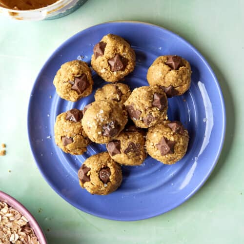 Overhead shot of no-bake protein balls stacked, studded with melted chocolate pieces.