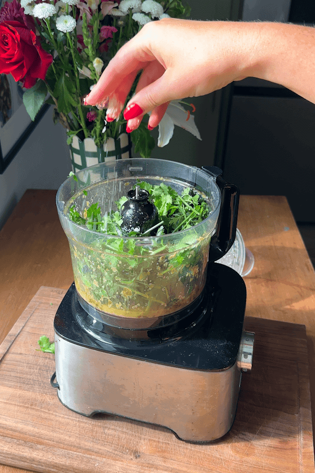 Parsley, coriander, garlic and capers being blended into a salsa verde dressing.