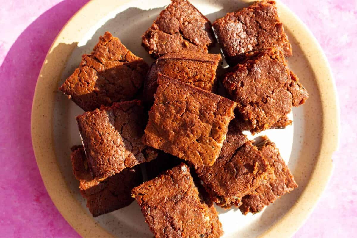 Overhead view of large plate of square pieces of chocolate brownies piled on plate.