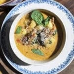 Bowl of creamy tuscan gnocchi soup with crispy sausage, kale, sundried tomatoes, parmesan and fresh basil.