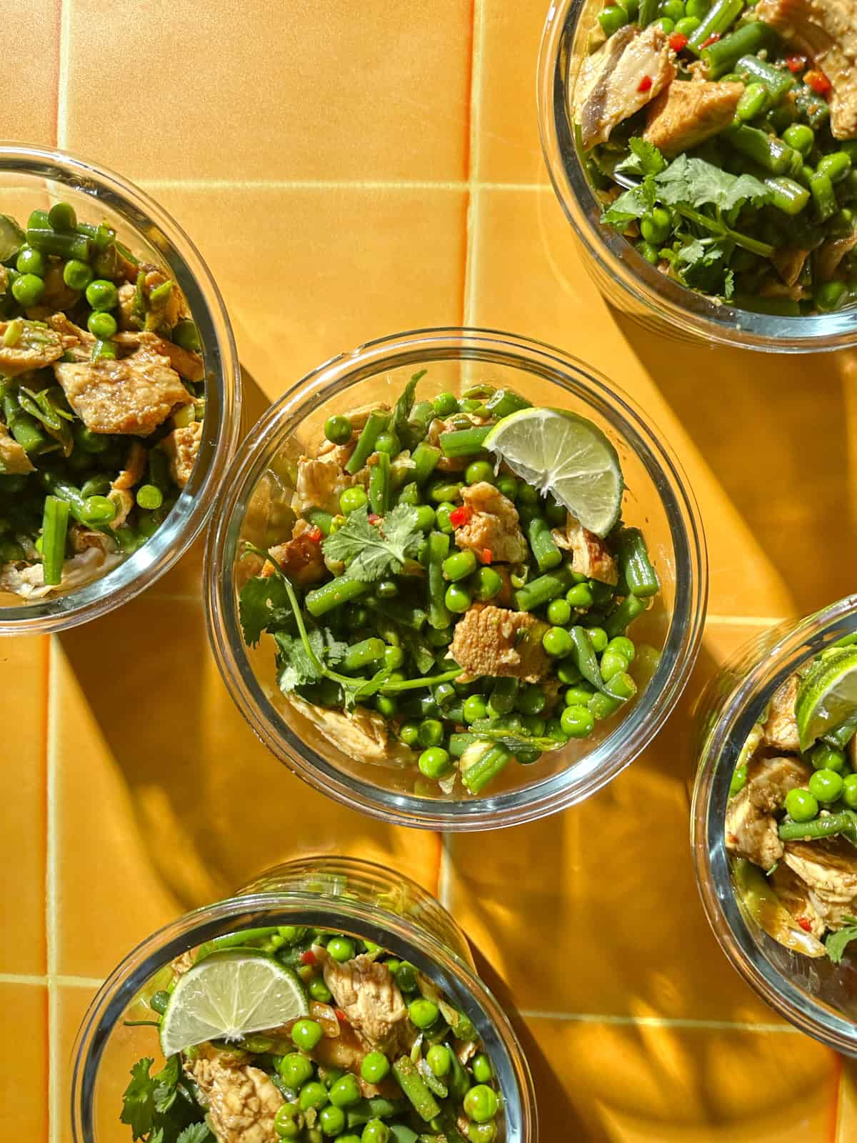Overhead shot of sesame soy chicken pea salad portioned into glass meal prep containers.