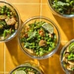 Meal prep containers of chicken pea salad with green beans, shredded chicken and lime wedges.
