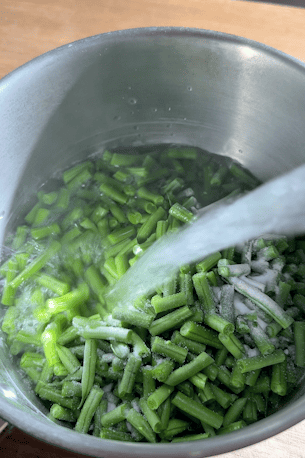 Chopped green beans in a pan of water.