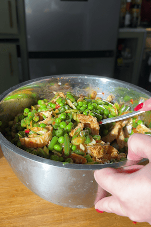 Chicken, peas and green beans being tossed in the sesame soy dressing.