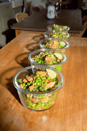 Five glass containers of chicken pea salad lined up on a wooden table.